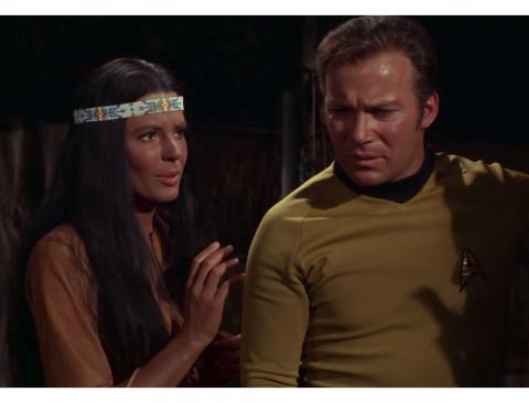 A white woman dressed as a Native American next to Captain Kirk.